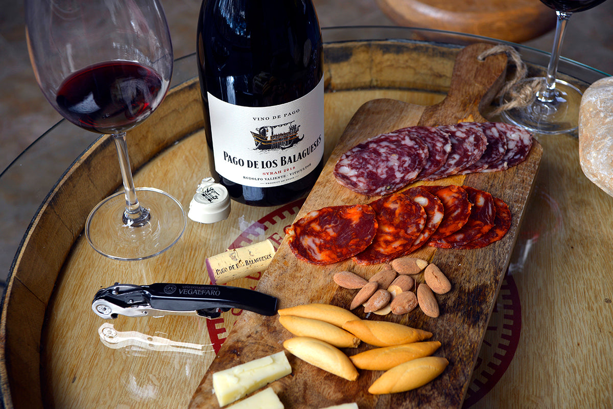 Vino de Pago de los Balagueses con tabla de embutidos, queso, almendras y picos sobre barrica de roble - Bodegas Vegalfaro